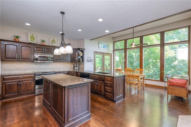 8355 Hallet St, Lenexa, KS 66215 - kitchen featuring appliances with stainless steel finishes, a peninsula, a center island, backsplash, and dark wood-type flooring