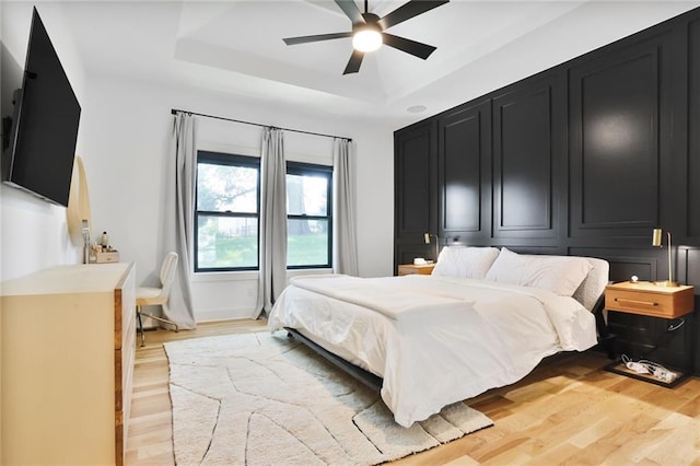 1245 NE Goshen Dr, Lees Summit, MO 64064 - bedroom featuring light wood-style flooring, a raised ceiling, and ceiling fan
