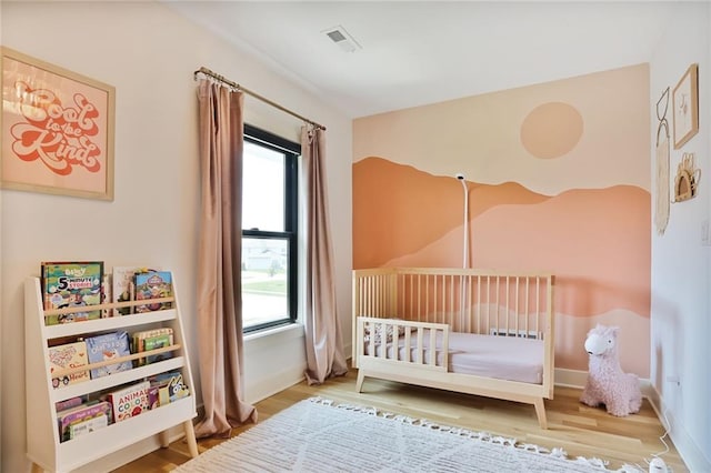 1245 NE Goshen Dr, Lees Summit, MO 64064 - bedroom featuring multiple windows, wood finished floors, and a nursery area