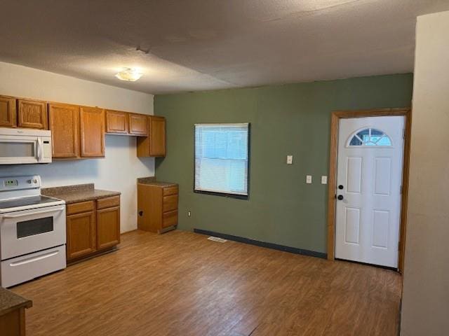 313 Shawnee St, Hiawatha, KS 66434 - kitchen with white appliances, brown cabinets, light wood-style floors, and dark countertops