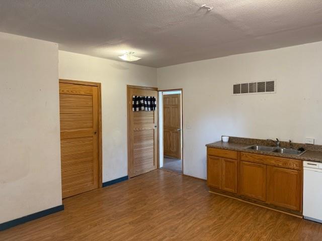 313 Shawnee St, Hiawatha, KS 66434 - kitchen with a sink, white dishwasher, wood finished floors, brown cabinets, and dark countertops