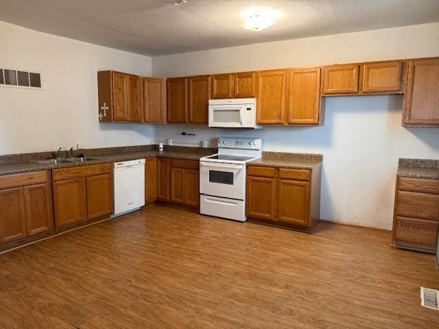 313 Shawnee St, Hiawatha, KS 66434 - kitchen featuring white appliances, brown cabinetry, wood finished floors, and dark countertops