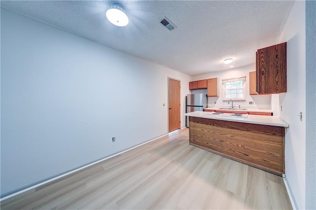 11321 W 77th Ter, Overland Park, KS 66214 - kitchen with light wood finished floors, freestanding refrigerator, a textured ceiling, a peninsula, and brown cabinetry