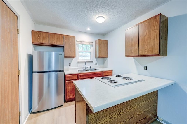 11321 W 77th Ter, Overland Park, KS 66214 - kitchen with freestanding refrigerator, a textured ceiling, a peninsula, light wood-type flooring, and light countertops
