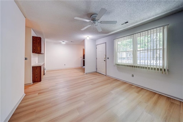 11321 W 77th Ter, Overland Park, KS 66214 - unfurnished living room featuring light wood-style flooring, a ceiling fan, and a textured ceiling