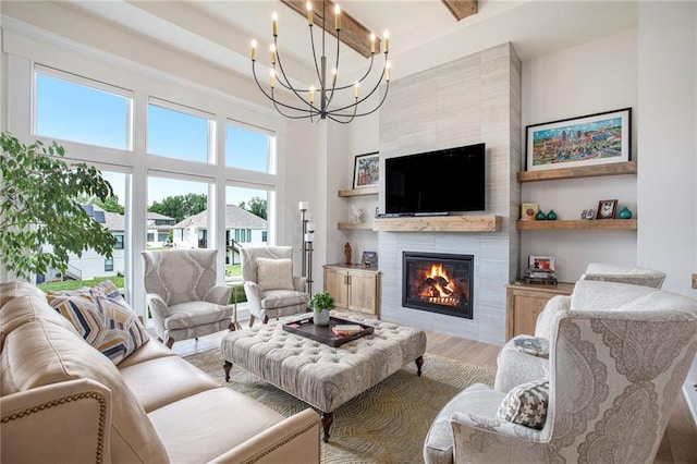 130 NW Ambersham Dr, Lees Summit, MO 64081 - living area featuring wood finished floors, a chandelier, healthy amount of natural light, a tiled fireplace, and a high ceiling