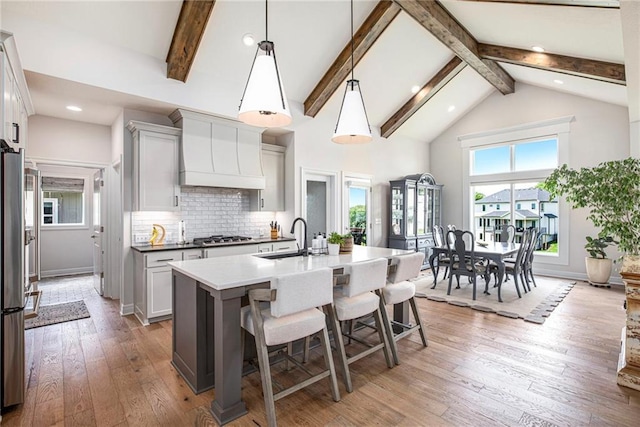 130 NW Ambersham Dr, Lees Summit, MO 64081 - kitchen with premium range hood, high vaulted ceiling, a breakfast bar, beamed ceiling, and a kitchen island with sink