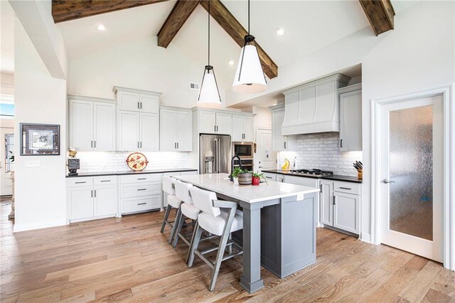 130 NW Ambersham Dr, Lees Summit, MO 64081 - kitchen featuring stainless steel appliances, beamed ceiling, light wood-style floors, decorative backsplash, and high vaulted ceiling