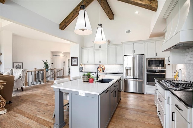 130 NW Ambersham Dr, Lees Summit, MO 64081 - kitchen with appliances with stainless steel finishes, custom range hood, light wood-type flooring, high vaulted ceiling, and a kitchen breakfast bar