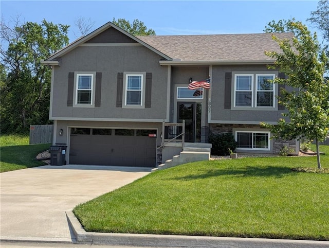 809 NW 4th St, Oak Grove, MO 64075 - bi-level home featuring a garage, driveway, a front lawn, and stucco siding