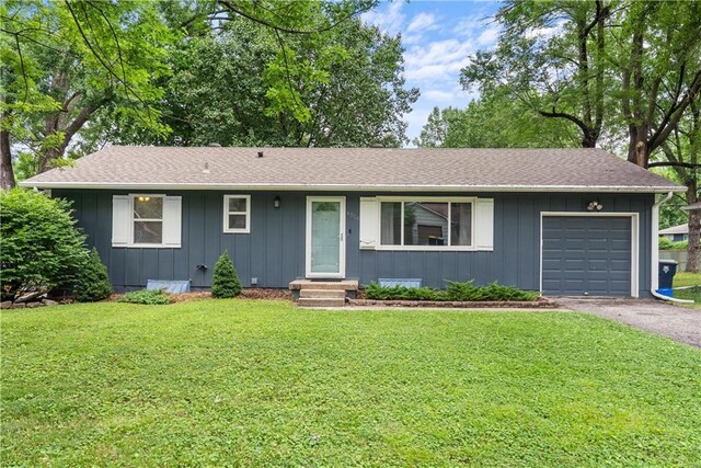 4510 E 113th St, Kansas City, MO 64137 - ranch-style home featuring board and batten siding, a garage, driveway, and a front lawn