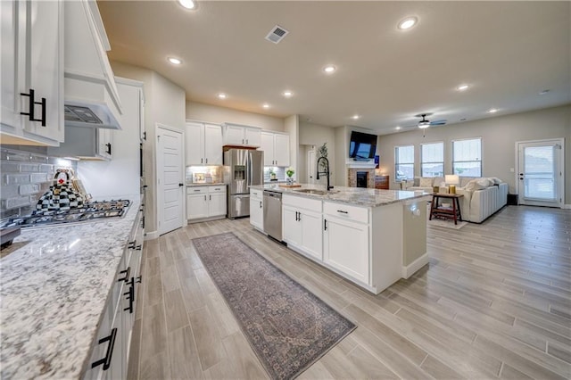 7526 Apache Dr, Lenexa, KS 66227 - kitchen featuring stainless steel appliances, a ceiling fan, open floor plan, custom range hood, and white cabinets