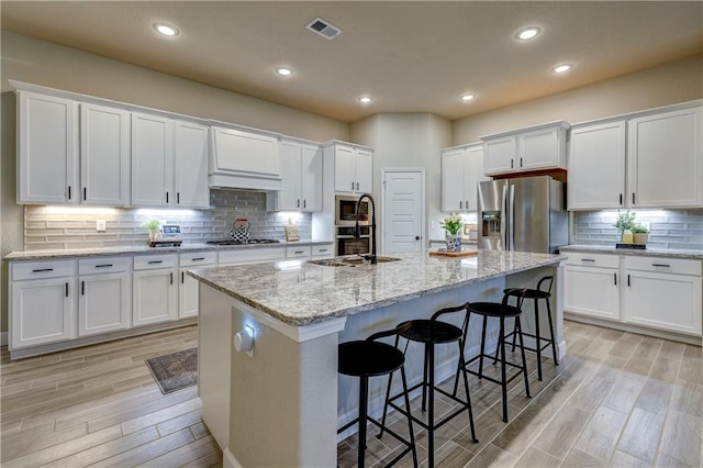 7526 Apache Dr, Lenexa, KS 66227 - kitchen with appliances with stainless steel finishes, light wood-style flooring, white cabinetry, a kitchen bar, and recessed lighting
