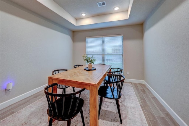 7526 Apache Dr, Lenexa, KS 66227 - dining room featuring light wood-style flooring, a raised ceiling, and a textured wall