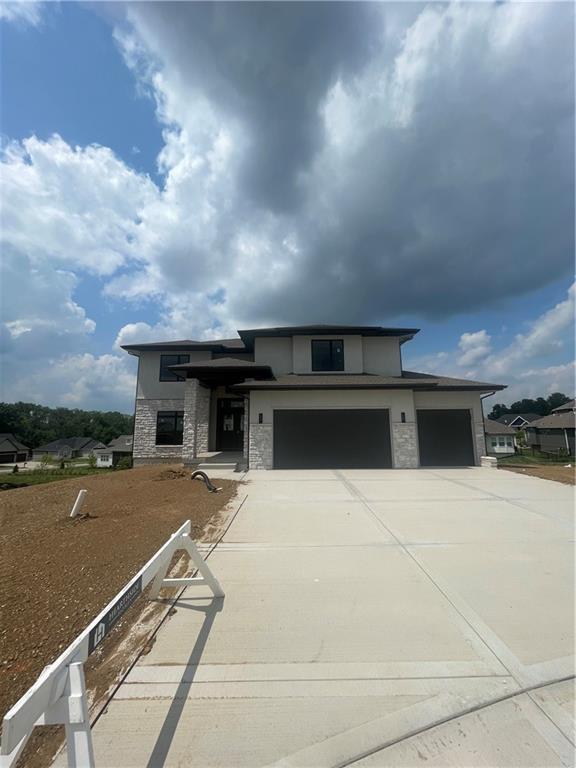 1824 Arbor Trl, Liberty, MO 64068 - prairie-style home featuring concrete driveway, stone siding, an attached garage, and stucco siding