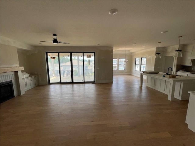 1824 Arbor Trl, Liberty, MO 64068 - unfurnished living room featuring light wood finished floors, a tiled fireplace, and ceiling fan
