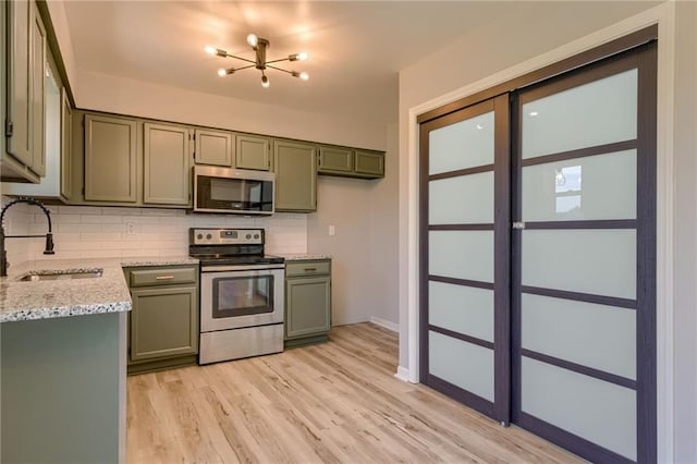 810 Bobwhite Dr, Peculiar, MO 64078 - kitchen featuring stainless steel appliances, green cabinetry, tasteful backsplash, a chandelier, and light wood-type flooring