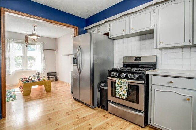 3920 S Milton Dr, Independence, MO 64055 - kitchen with appliances with stainless steel finishes, light wood-type flooring, tasteful backsplash, light countertops, and pendant lighting