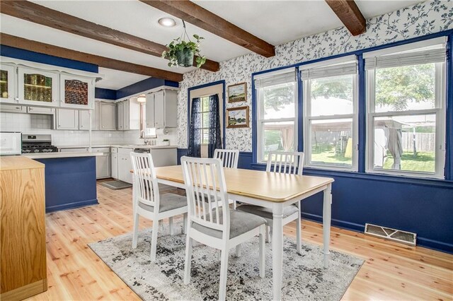 3920 S Milton Dr, Independence, MO 64055 - dining space with wallpapered walls, light wood-type flooring, and beam ceiling