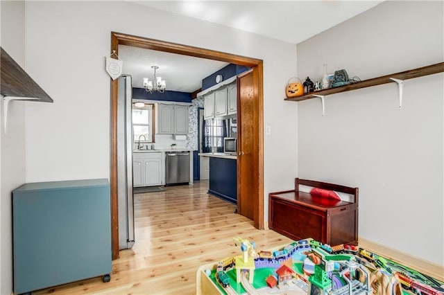 3920 S Milton Dr, Independence, MO 64055 - recreation room with a sink, light wood finished floors, and a chandelier