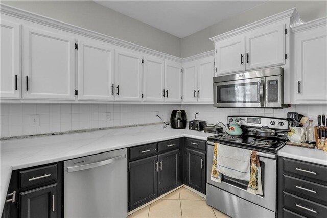 408 Eisenhower Rd, Baldwin City, KS 66006 - kitchen with appliances with stainless steel finishes, dark cabinetry, white cabinetry, and tasteful backsplash