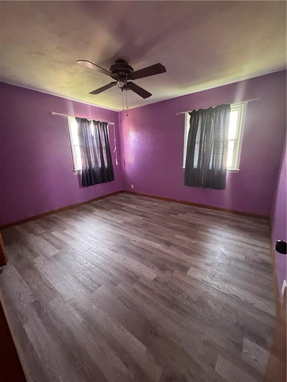1110 S Plummer Ave, Chanute, KS 66720 - unfurnished room with ceiling fan, wood finished floors, and baseboards