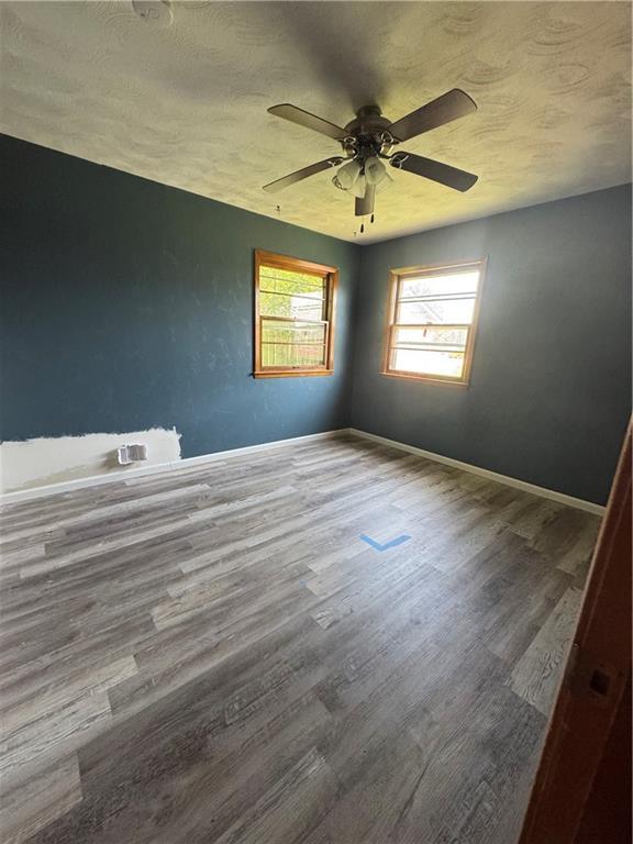 1110 S Plummer Ave, Chanute, KS 66720 - empty room featuring wood finished floors, ceiling fan, a textured ceiling, and baseboards