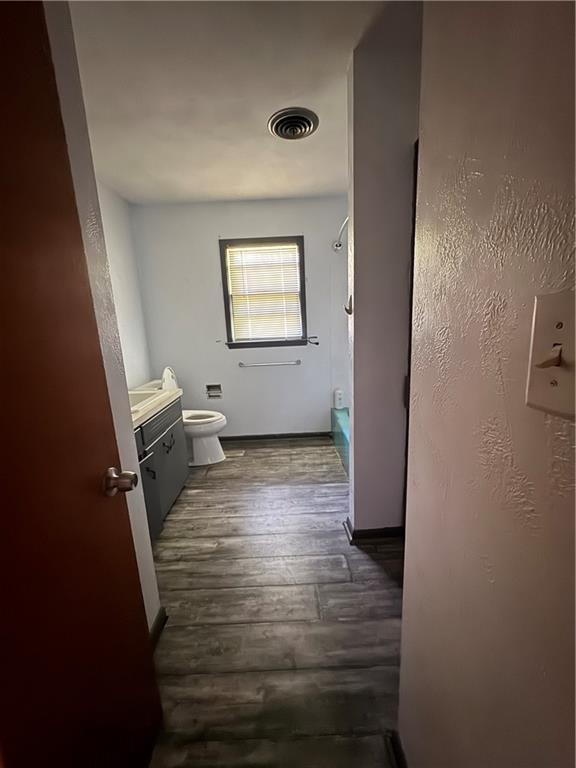 1110 S Plummer Ave, Chanute, KS 66720 - bathroom featuring vanity, toilet,  shower combination, wood finished floors, and baseboards