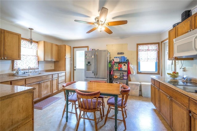 1401 Osage St, Leavenworth, KS 66048 - kitchen featuring stainless steel fridge, white microwave, ceiling fan, black electric cooktop, and brown cabinets