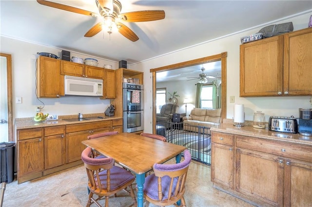 1401 Osage St, Leavenworth, KS 66048 - kitchen featuring white microwave, stainless steel double oven, ceiling fan, black electric cooktop, and brown cabinets