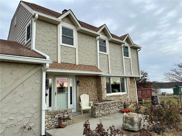 26609 S Red Bud Rd, Freeman, MO 64746 - view of front of house featuring stucco siding, stone siding, and roof with shingles
