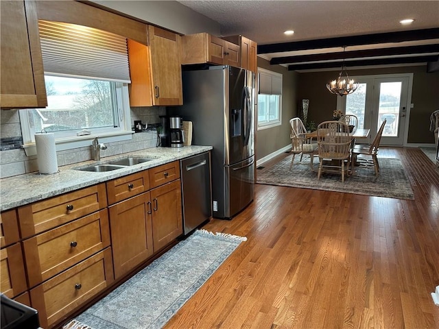 26609 S Red Bud Rd, Freeman, MO 64746 - kitchen with appliances with stainless steel finishes, brown cabinetry, beam ceiling, wood finished floors, and a chandelier