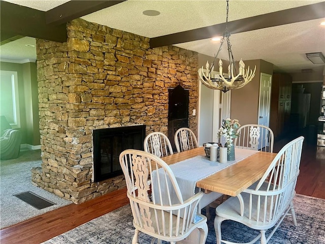 26609 S Red Bud Rd, Freeman, MO 64746 - dining room with wood finished floors, beamed ceiling, a chandelier, a textured ceiling, and a glass covered fireplace