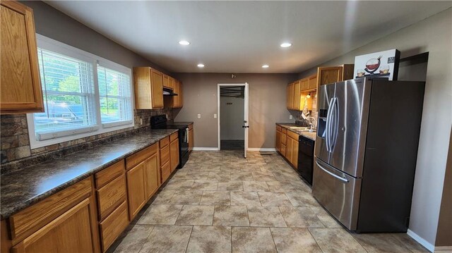 411 S Fulton St, Butler, MO 64730 - kitchen featuring black appliances, decorative backsplash, under cabinet range hood, recessed lighting, and dark countertops