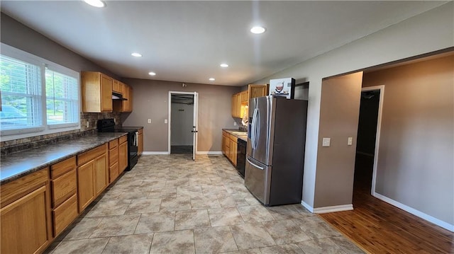 411 S Fulton St, Butler, MO 64730 - kitchen featuring stainless steel refrigerator with ice dispenser, black range with electric stovetop, dark countertops, recessed lighting, and under cabinet range hood