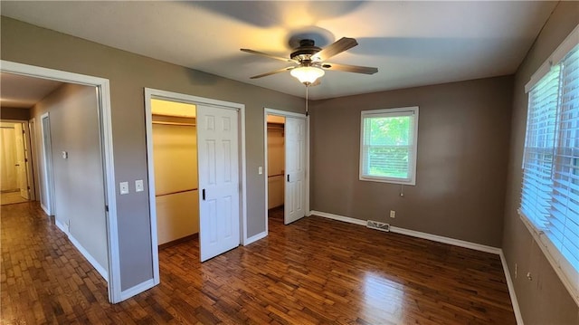 411 S Fulton St, Butler, MO 64730 - unfurnished bedroom featuring dark wood finished floors, multiple closets, and ceiling fan