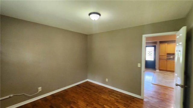 411 S Fulton St, Butler, MO 64730 - spare room featuring wood finished floors and baseboards