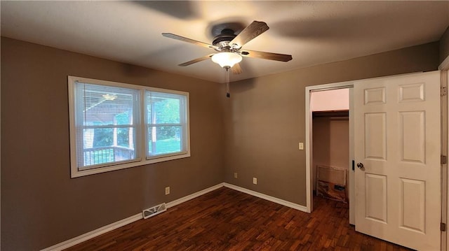 411 S Fulton St, Butler, MO 64730 - unfurnished bedroom with dark wood-type flooring, a closet, a spacious closet, and a ceiling fan