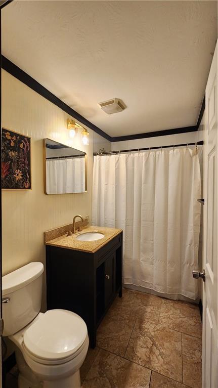 411 S Fulton St, Butler, MO 64730 - full bathroom featuring vanity, stone tile floors, and crown molding