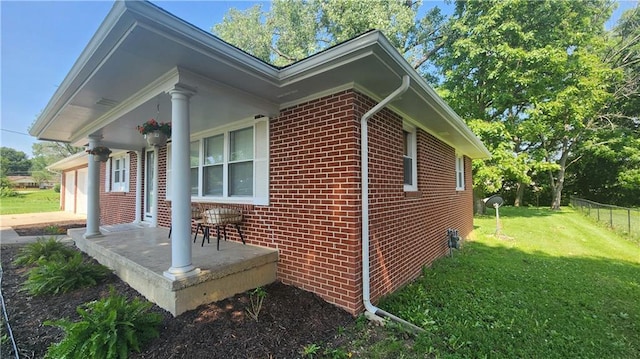 411 S Fulton St, Butler, MO 64730 - view of home's exterior featuring brick siding, a porch, and a garage
