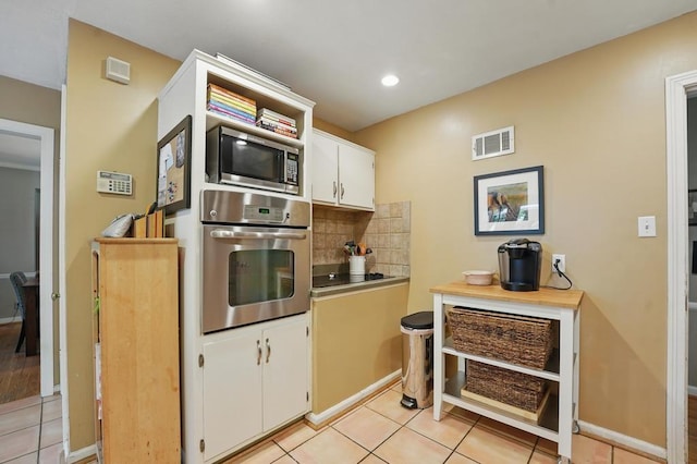 8604 Sagamore Rd, Leawood, KS 66206 - kitchen featuring appliances with stainless steel finishes, light tile patterned flooring, white cabinets, tasteful backsplash, and recessed lighting