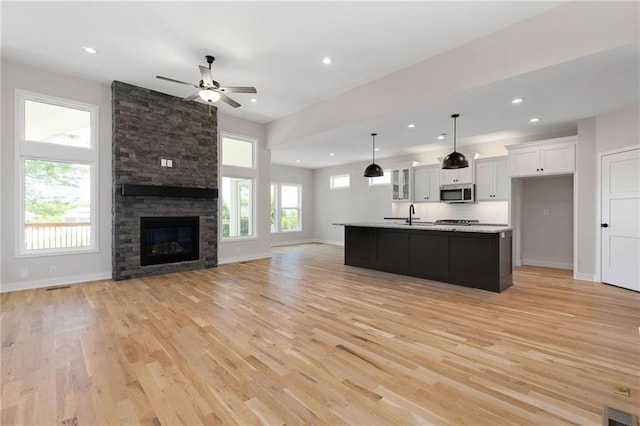 31501 W 86th Ct, De Soto, KS 66018 - kitchen with stainless steel microwave, open floor plan, light wood-style flooring, white cabinetry, and recessed lighting