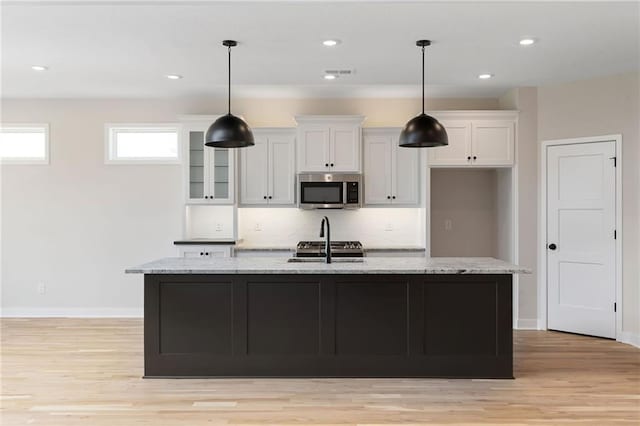 31501 W 86th Ct, De Soto, KS 66018 - kitchen featuring stainless steel microwave, white cabinetry, light wood-type flooring, a kitchen island with sink, and recessed lighting