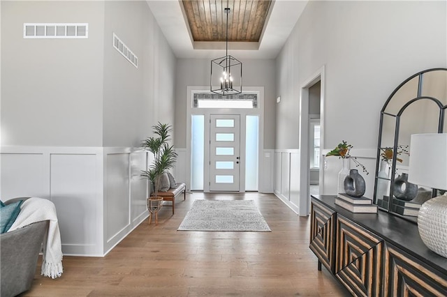 6113 Barth Rd, Shawnee, KS 66226 - entrance foyer featuring a raised ceiling, a decorative wall, a chandelier, wood finished floors, and a wainscoted wall