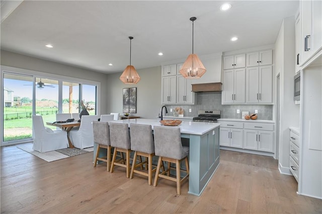 6113 Barth Rd, Shawnee, KS 66226 - kitchen featuring gas range, premium range hood, light countertops, tasteful backsplash, and light wood-style floors