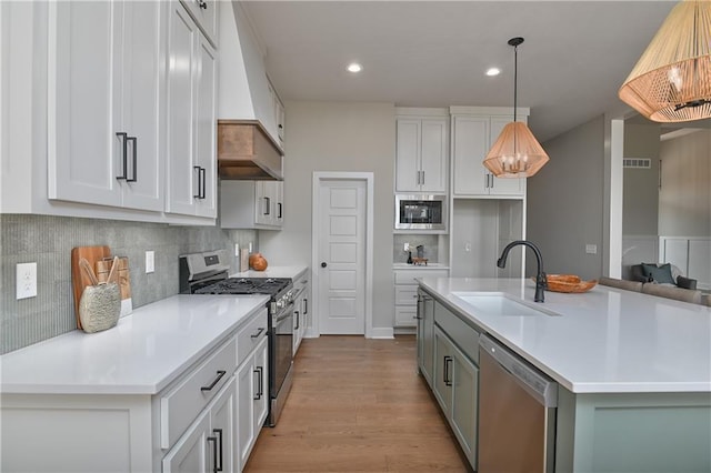 6113 Barth Rd, Shawnee, KS 66226 - kitchen with stainless steel appliances, a sink, wood finished floors, light countertops, and decorative backsplash
