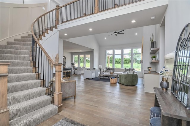 6039 Apache Dr, Shawnee, KS 66226 - living area featuring stairway, wood finished floors, ceiling fan, recessed lighting, and high vaulted ceiling