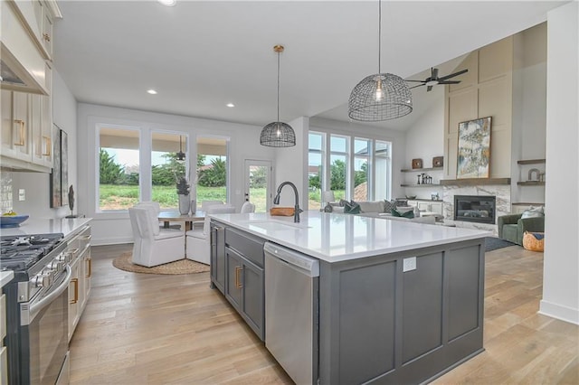 6039 Apache Dr, Shawnee, KS 66226 - kitchen with appliances with stainless steel finishes, a sink, gray cabinets, a glass covered fireplace, and healthy amount of natural light