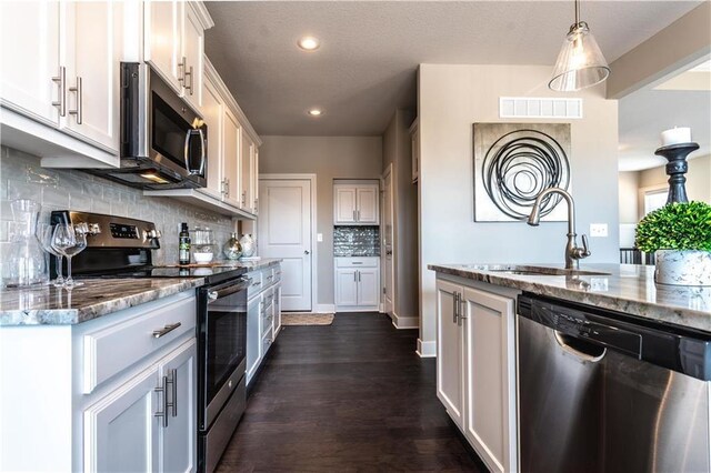 31432 W 85th Ter, De Soto, KS 66018 - kitchen featuring appliances with stainless steel finishes, light stone counters, tasteful backsplash, dark wood finished floors, and recessed lighting