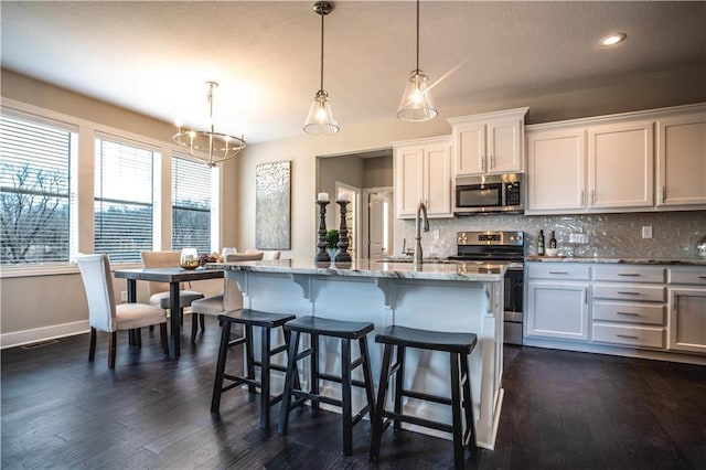 31432 W 85th Ter, De Soto, KS 66018 - kitchen with stainless steel appliances, backsplash, light stone counters, dark wood-style flooring, and a kitchen bar